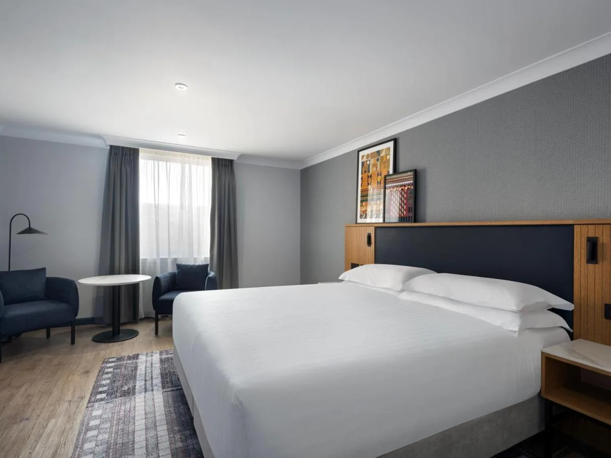 a hotel room with a large white bed and a desk at Edinburgh Marriott Hotel Holyrood in Edinburgh
