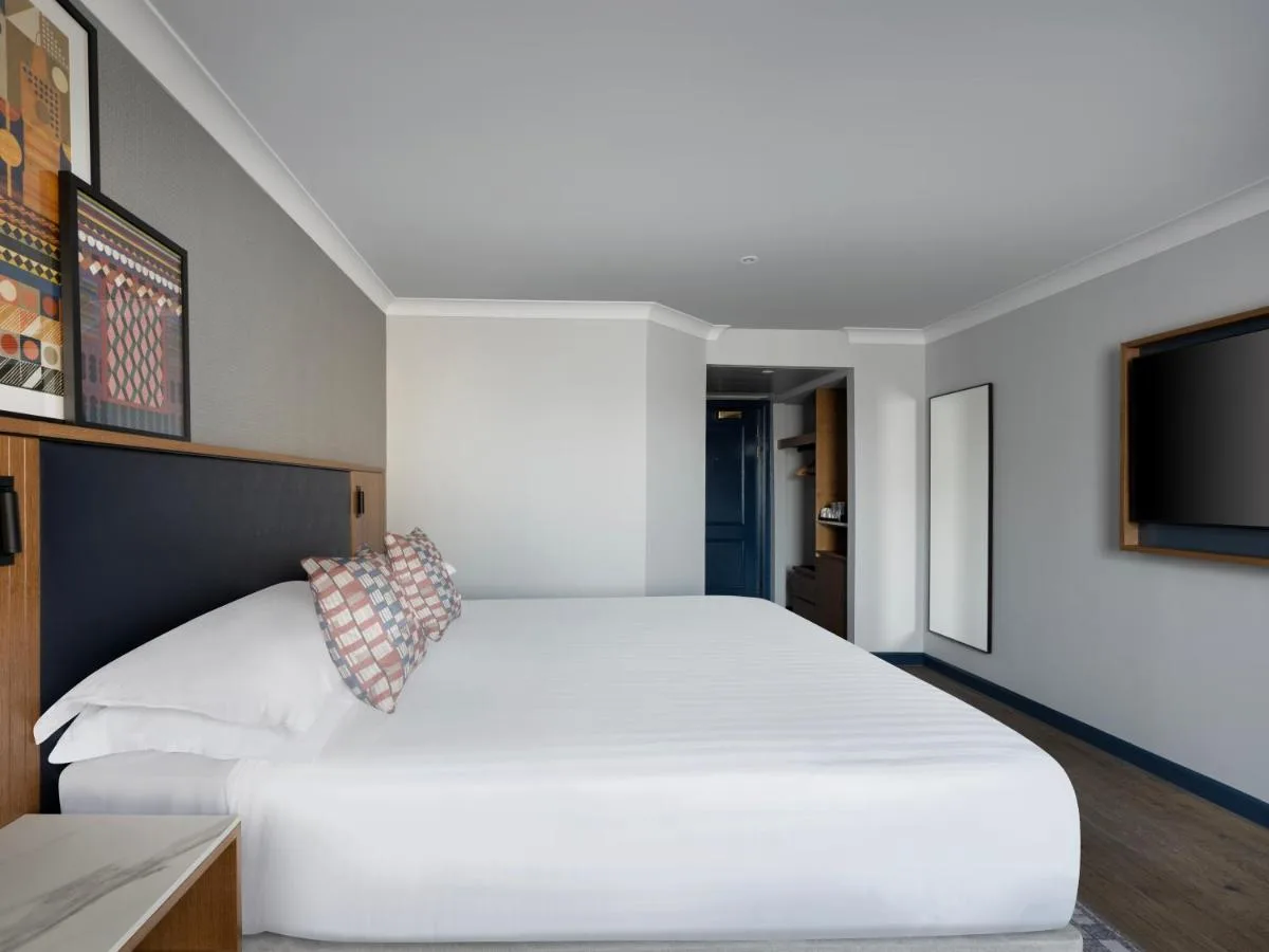 a bedroom with a large white bed and a flat screen tv at Edinburgh Marriott Hotel Holyrood in Edinburgh
