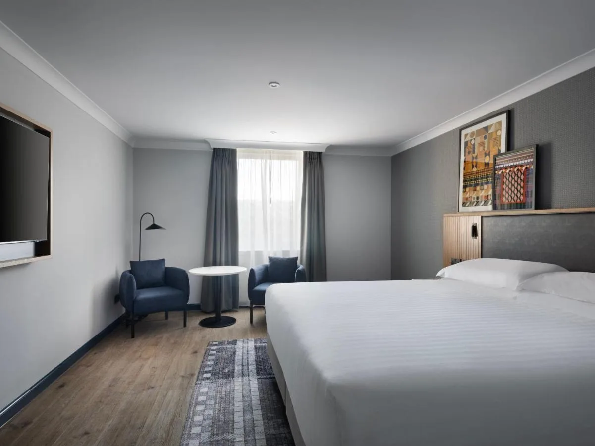a hotel room with a bed and a table and chairs at Edinburgh Marriott Hotel Holyrood in Edinburgh